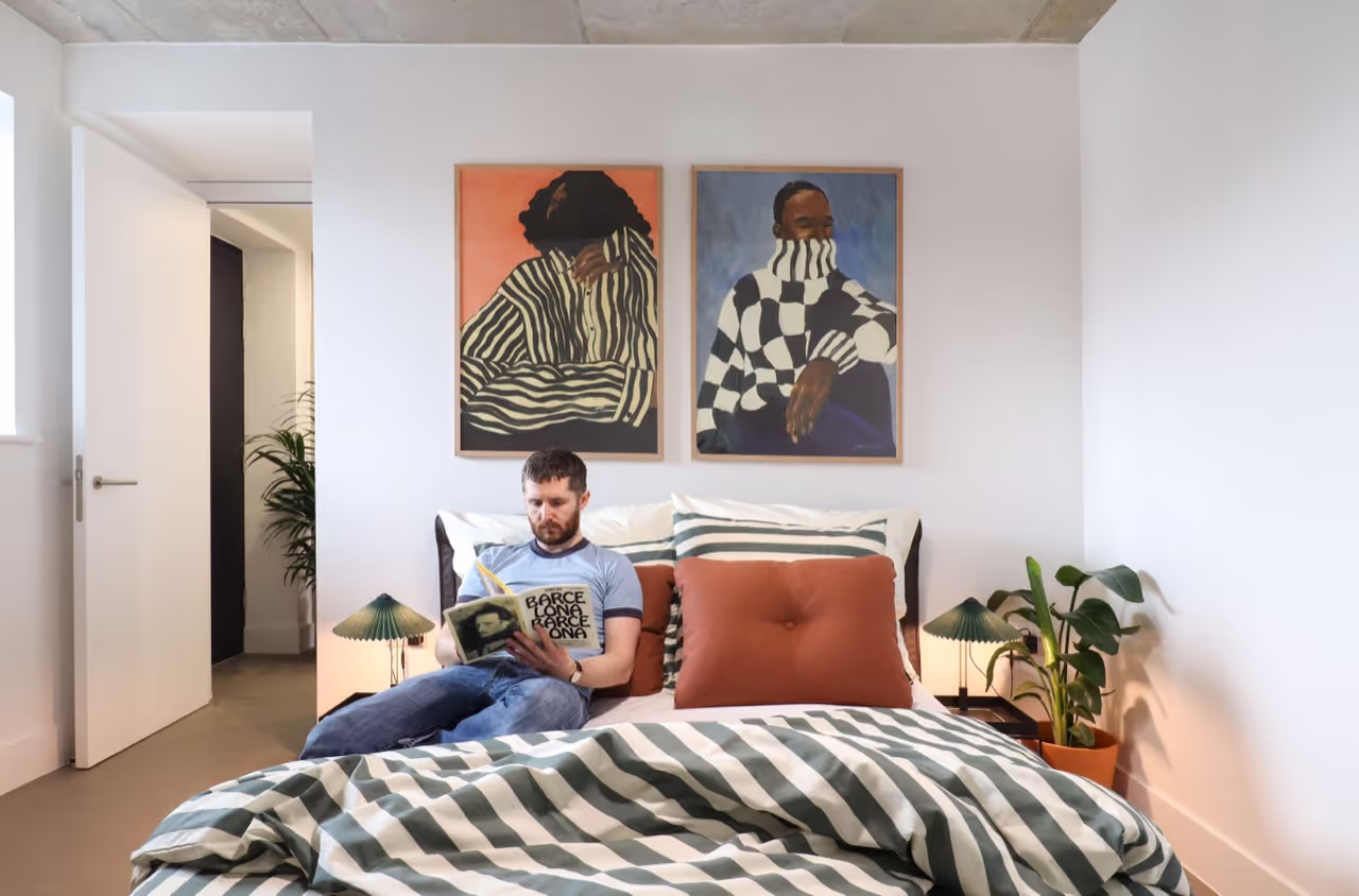 Man reading on a bed in a OllO Living appartment.